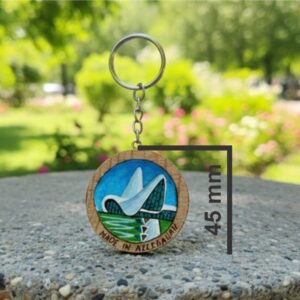 A detailed handcrafted miniature painting of the Heydar Aliyev Center in Baku, applied with fine brushes onto a natural wood slice keychain with bark edge, by Artirs Family Craft master artisans.