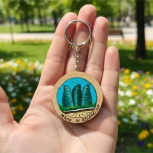 Hand-painted miniature artwork of Baku Flame Towers on a natural wood slice keychain, created with fine brushes by Artirs Family Craft.