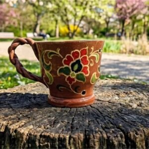 A high-definition front view of the unique KÜP Ceramics House handcrafted 1-of-1 ceramic mug featuring intricate geometric floral carpet motifs and calligraphy hand-painted directly onto a matte raw earthy clay body, with a detailed knitted-look tactile textured handle, certified authentic by master Kamran.